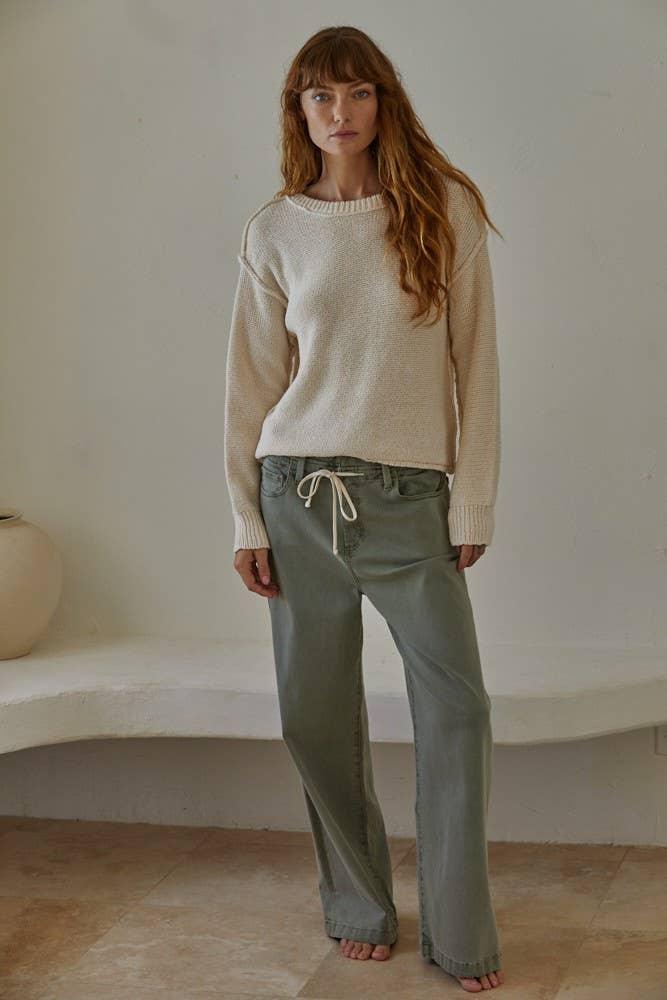 Woman in cozy cream sweater and olive drawstring pants, coastal casual style
