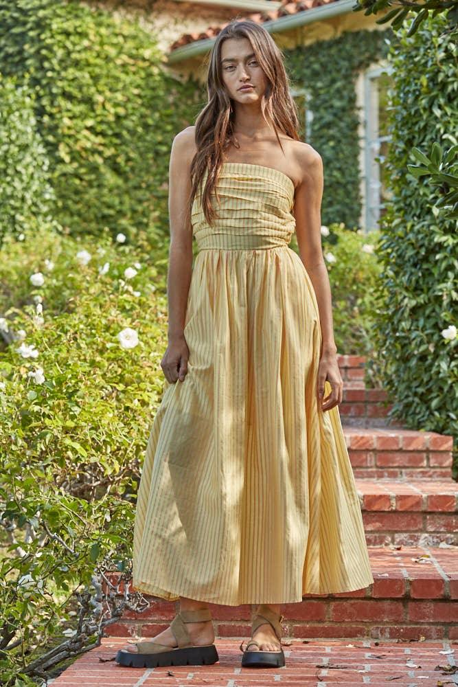 Woman in yellow striped strapless maxi dress with platform sandals, garden setting