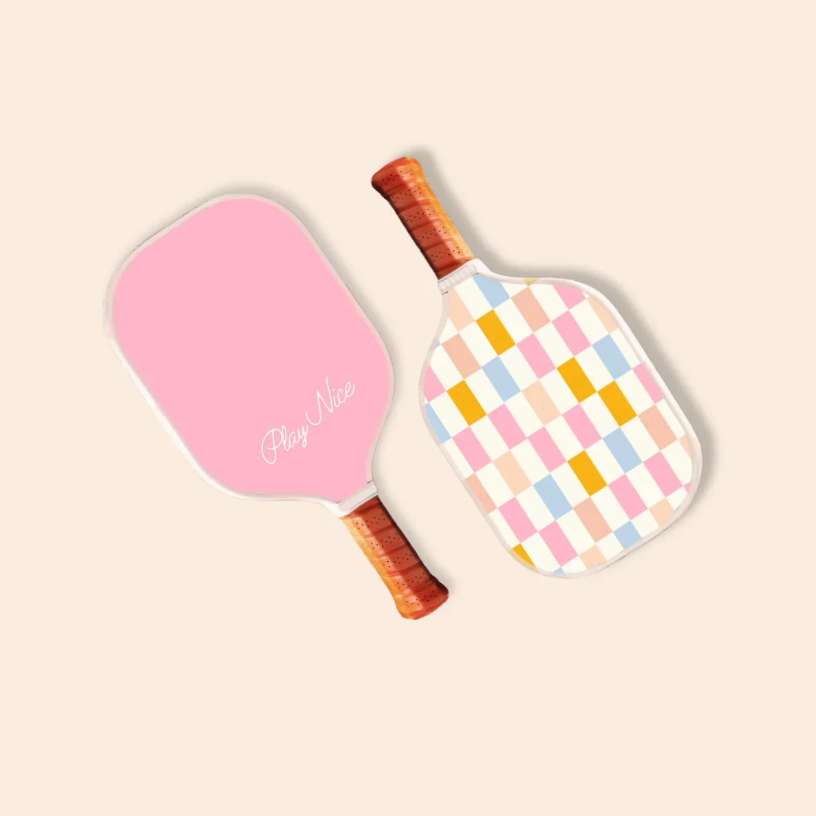 Pink and pastel checkered pickleball paddles with 'Play Nice' script, perfect for beach days and outdoor fun