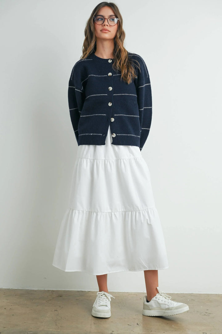 Navy striped cardigan with white tiered midi skirt and white sneakers, coastal style outfit