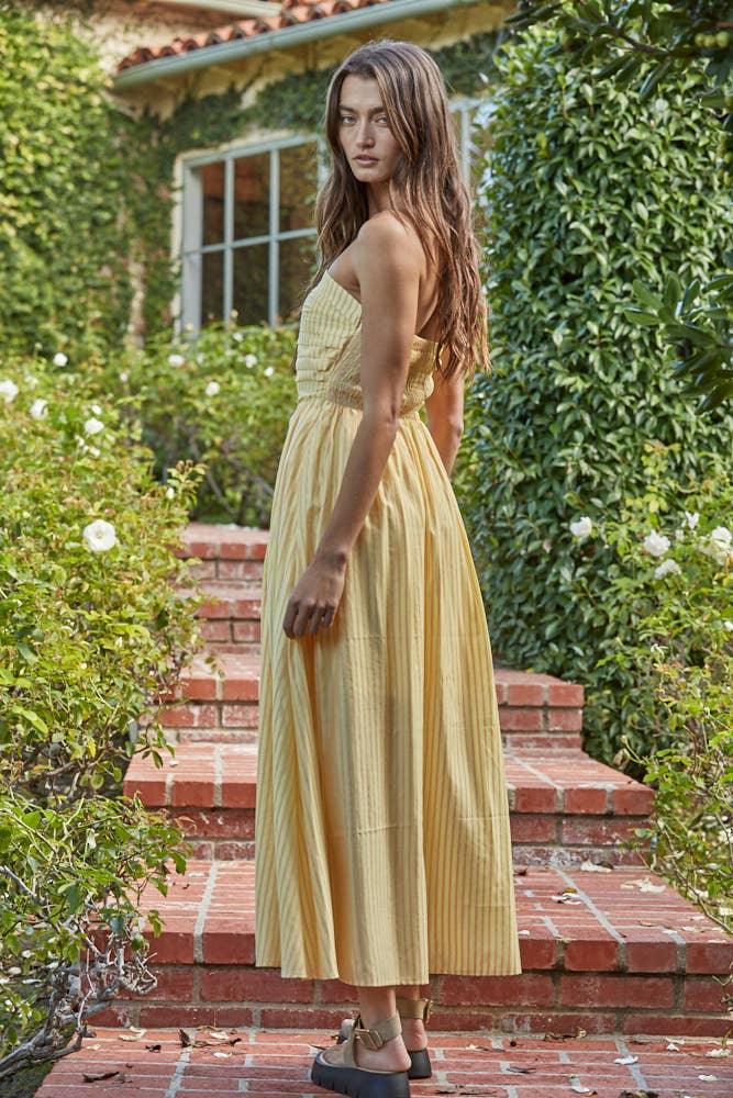Woman in yellow striped sundress on brick steps, coastal garden setting, perfect for beach days and PNW adventures