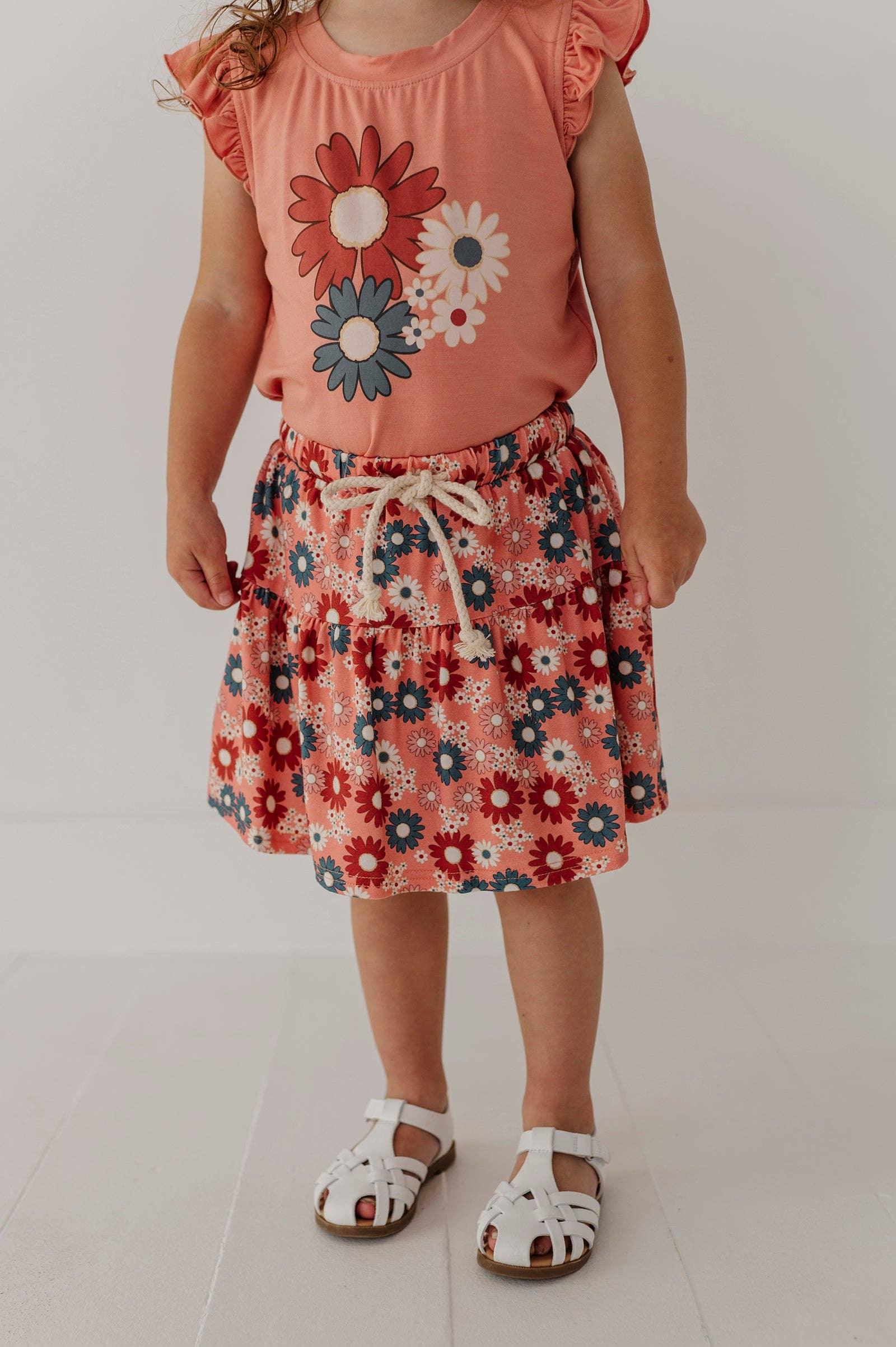 Toddler in coral floral top and matching skirt with white sandals, perfect for beach days and outdoor adventures.
