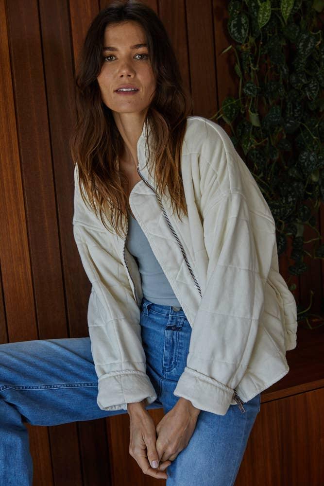 Cream quilted jacket with zipper, styled with blue jeans for coastal outdoor adventures