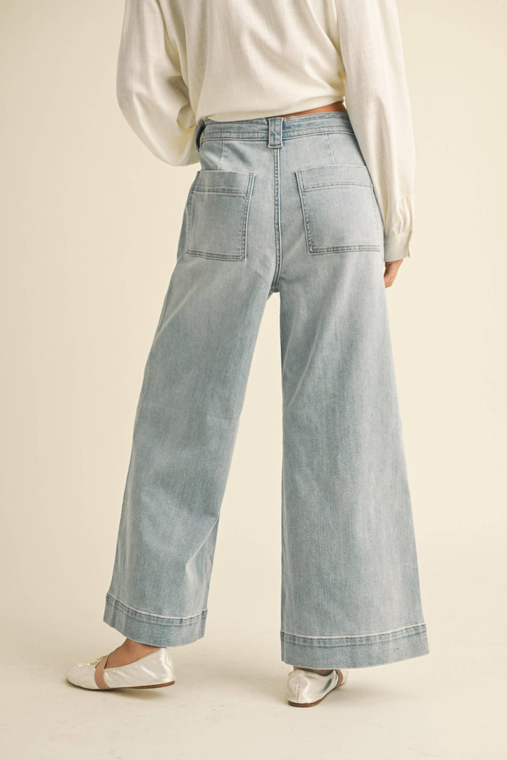 Light wash wide-leg denim jeans with back pockets, paired with cream blouse and white flats