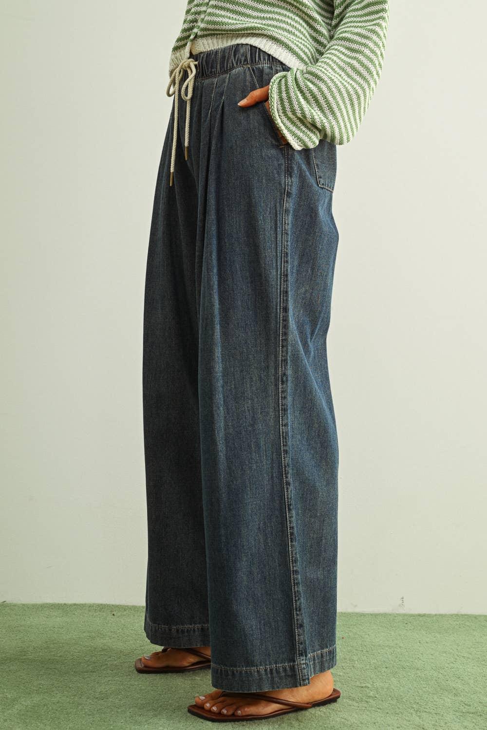 Wide-leg denim pants with drawstring waist, paired with striped sweater and sandals