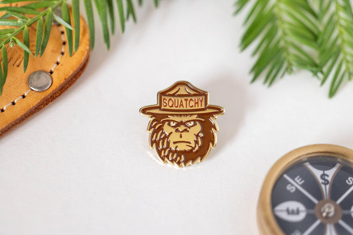 Squatchy enamel pin with ranger hat, forest-themed accessory for outdoor lovers
