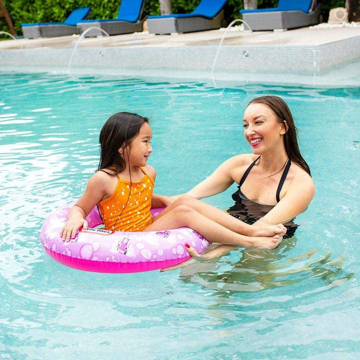 Child in pink float ring with adult in pool, enjoying summer water fun