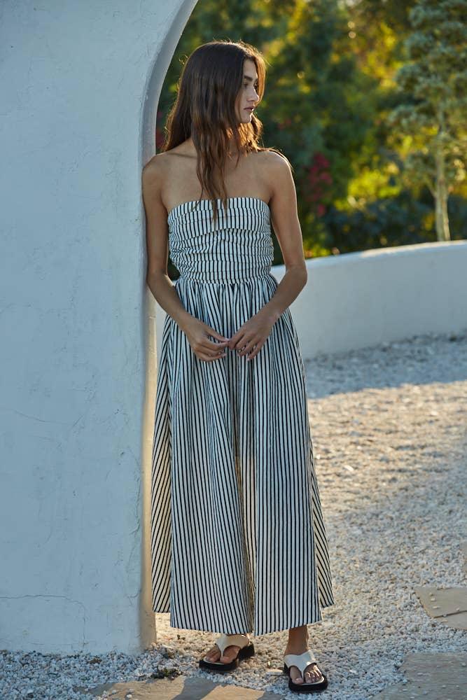 Woman in black and white striped strapless maxi dress, coastal outdoor style