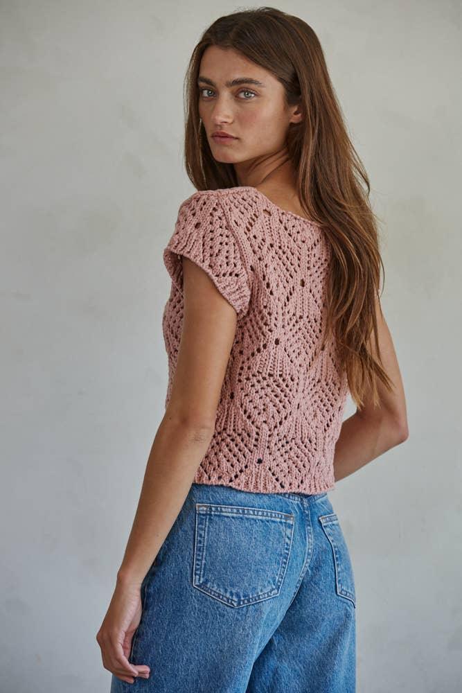 Pink knitted off-shoulder top with lace pattern paired with blue jeans