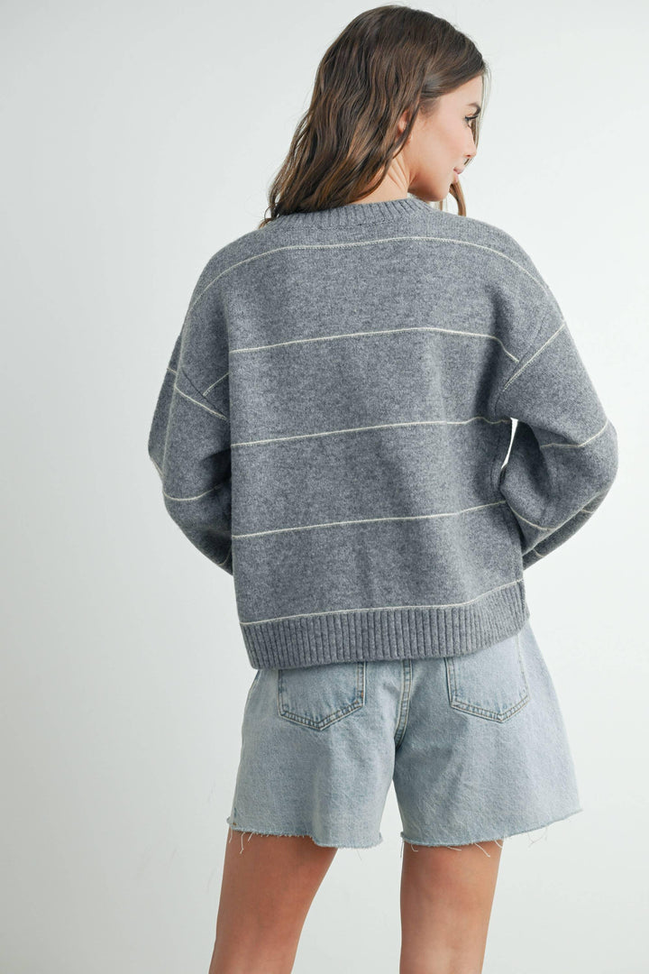 Gray striped knit sweater with ribbed hem, paired with light denim shorts for casual coastal style