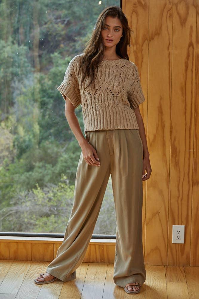 Woman in cozy knit crop top and wide-leg pants, styled for casual comfort near window with forest view