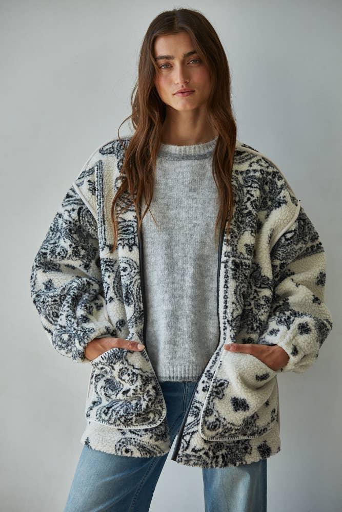 Cozy patterned fleece cardigan for coastal PNW style, layered over gray sweater and jeans