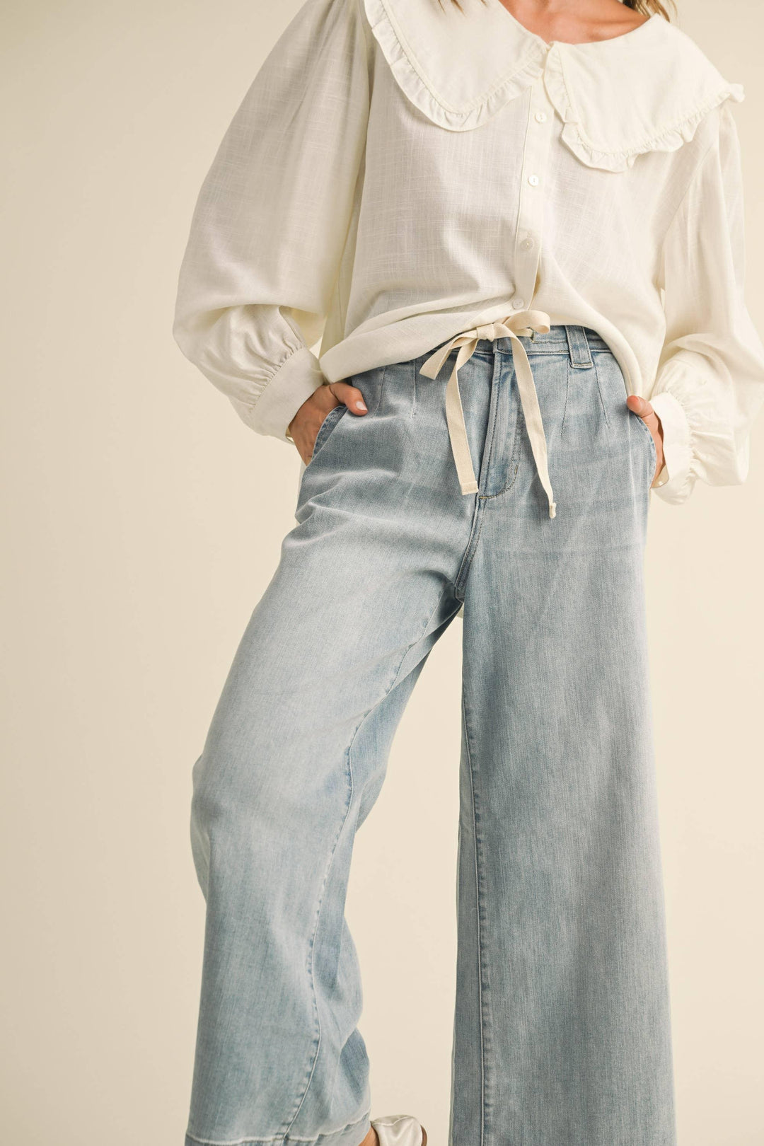 Cream ruffle collar blouse with puff sleeves paired with light wash wide leg jeans for coastal style