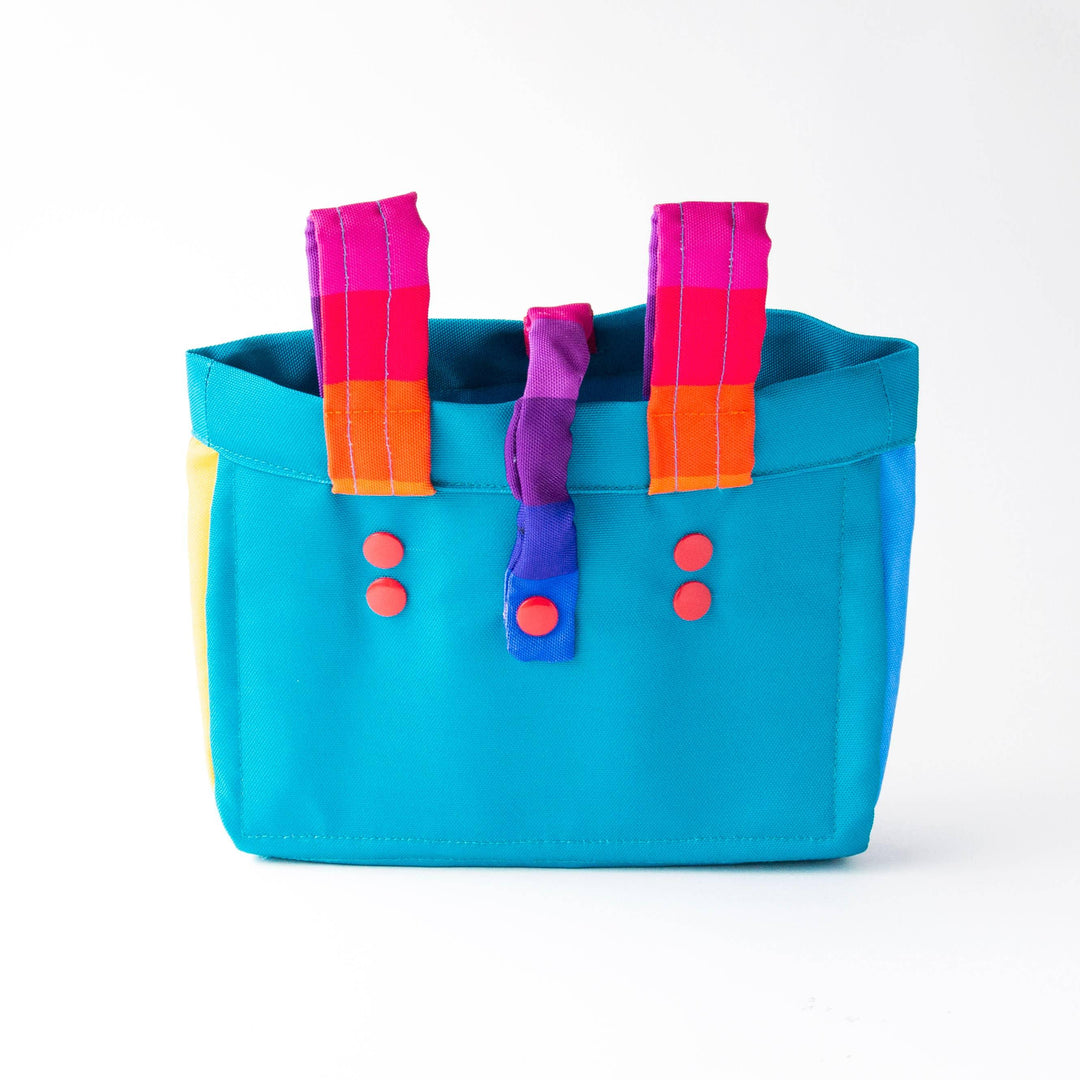 Vibrant turquoise tote with rainbow straps and red buttons, perfect for beach days and outdoor adventures.