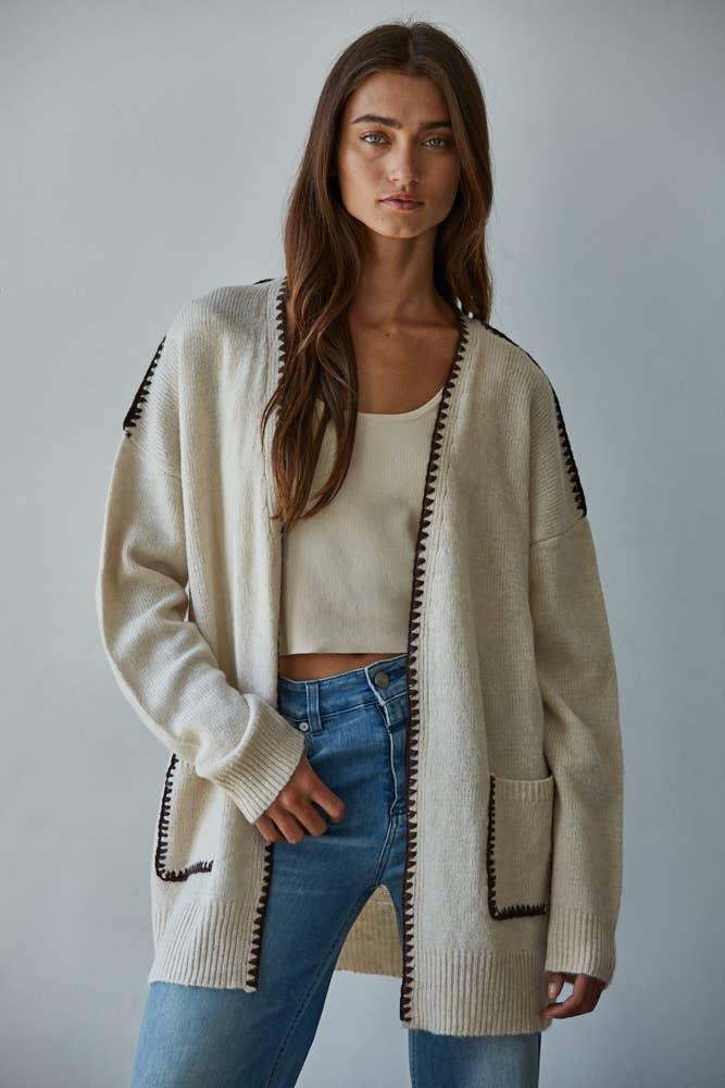 Cream knit cardigan with black trim, styled with crop top and jeans for coastal PNW weekend vibes