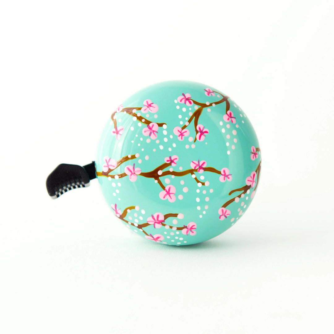 Turquoise bike bell with pink cherry blossom design, perfect for coastal rides and outdoor adventures.