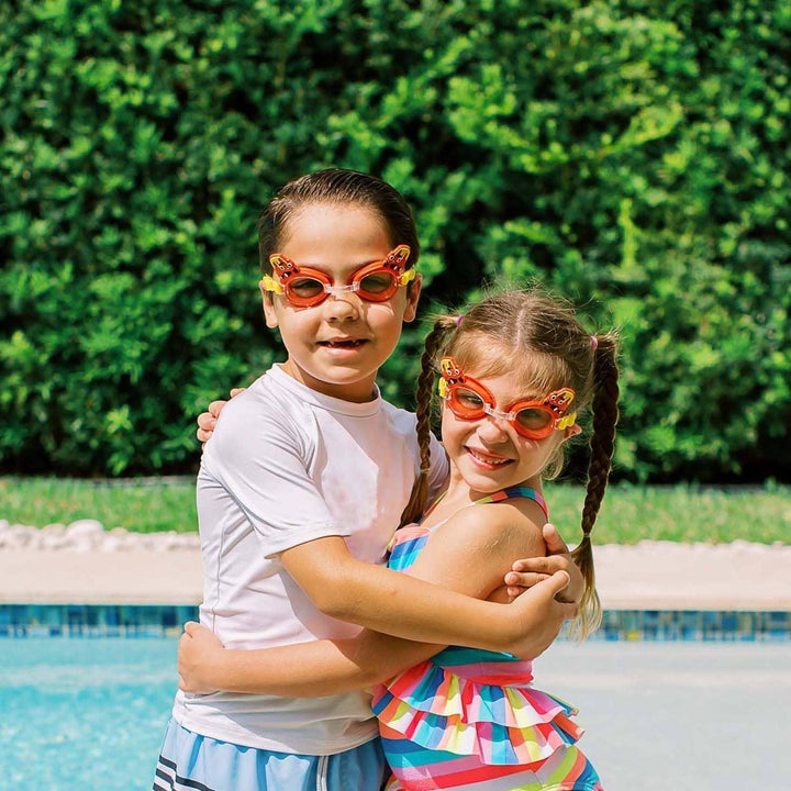 Two children hugging by a pool wearing orange PoolCandy swim goggles