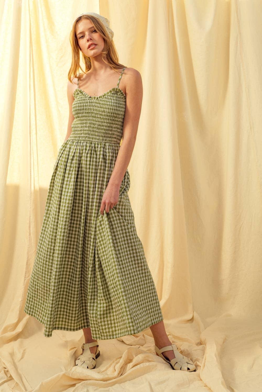 Woman in green gingham midi dress with smocked bodice, cream sandals, and headscarf against soft yellow backdrop