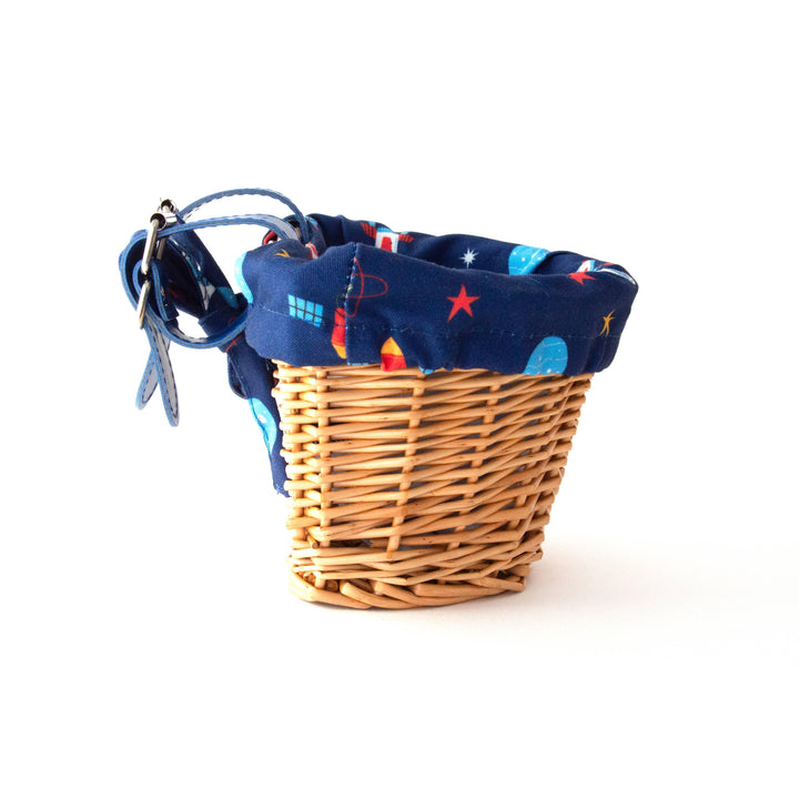 Woven bike basket with space-themed navy liner, stars, planets, and attachable straps for outdoor adventures.