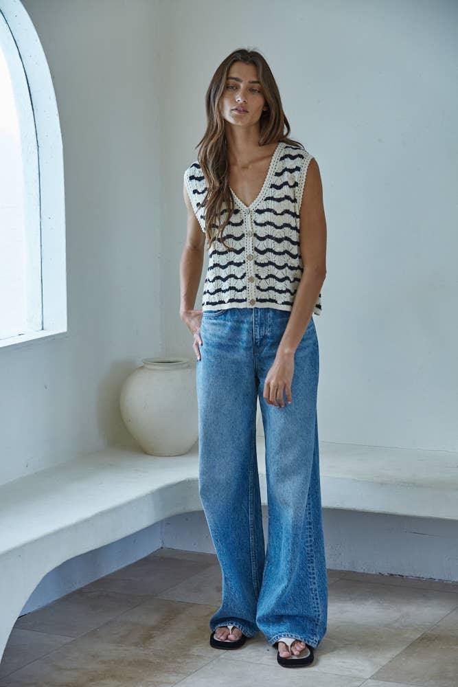 Woman in wavy striped knit vest and wide-leg denim jeans, coastal style outfit
