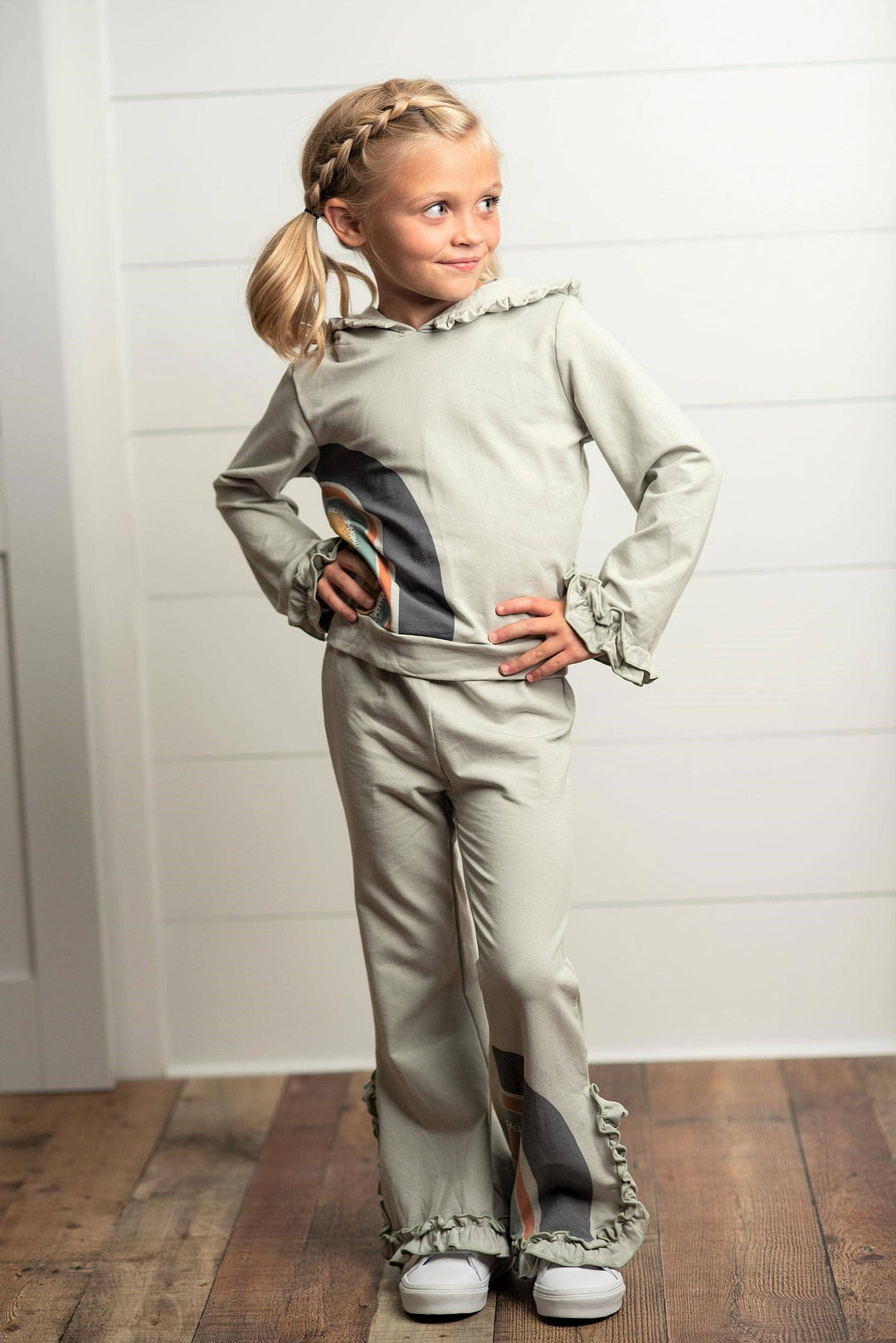 Young girl wearing an Oopsie Daisy gray sage rainbow hooded sweatsuit lounge set.