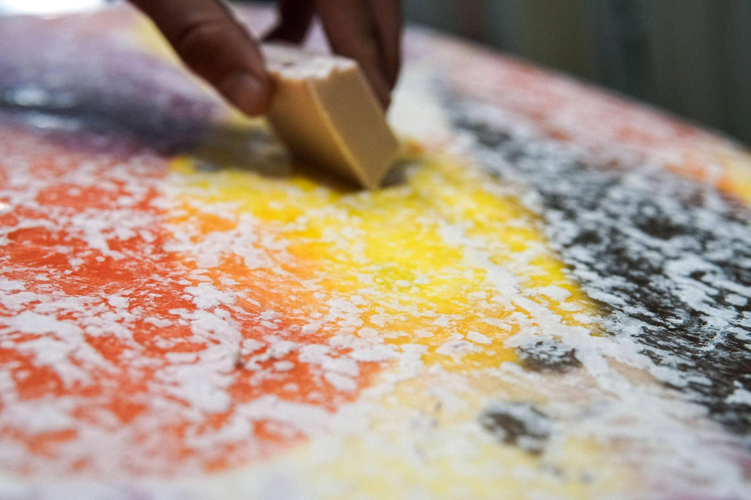 Hand waxing colorful surfboard with wax block for grip and performance