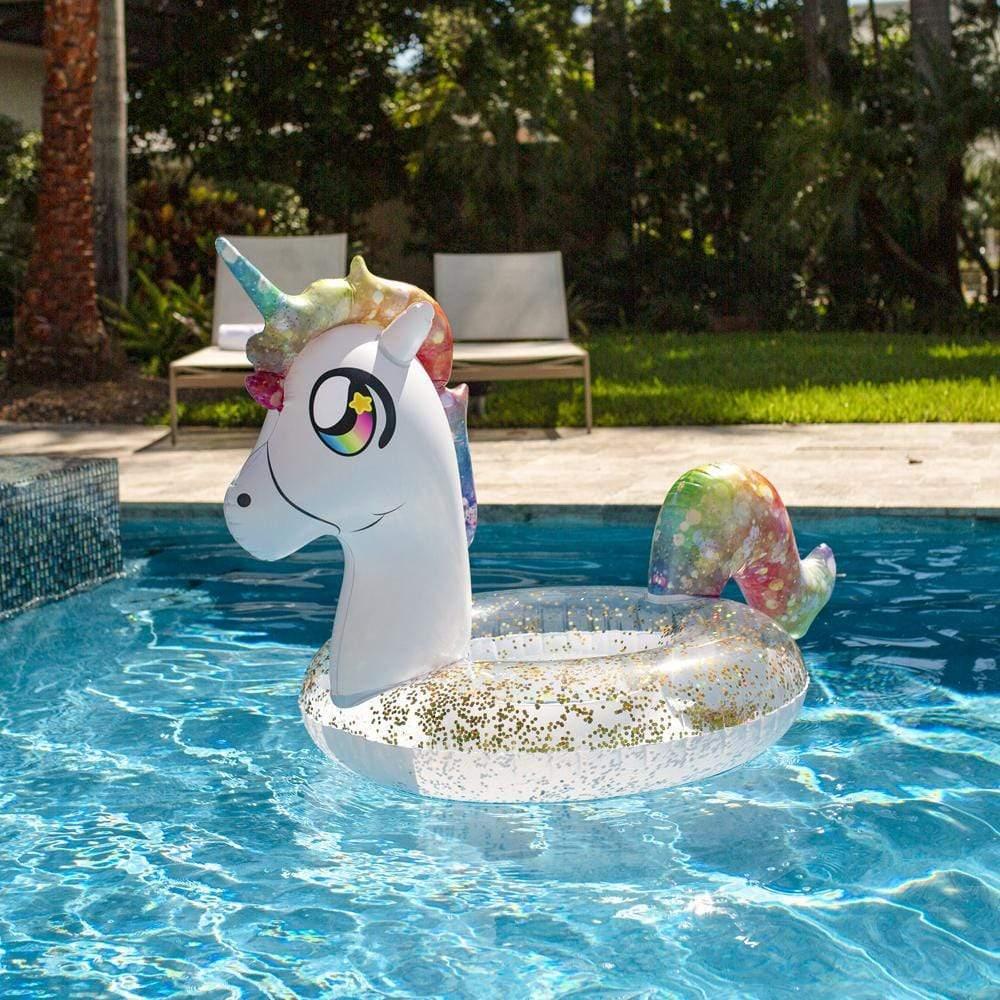 Rainbow unicorn pool float with gold glitter, floating in backyard swimming pool for summer fun.