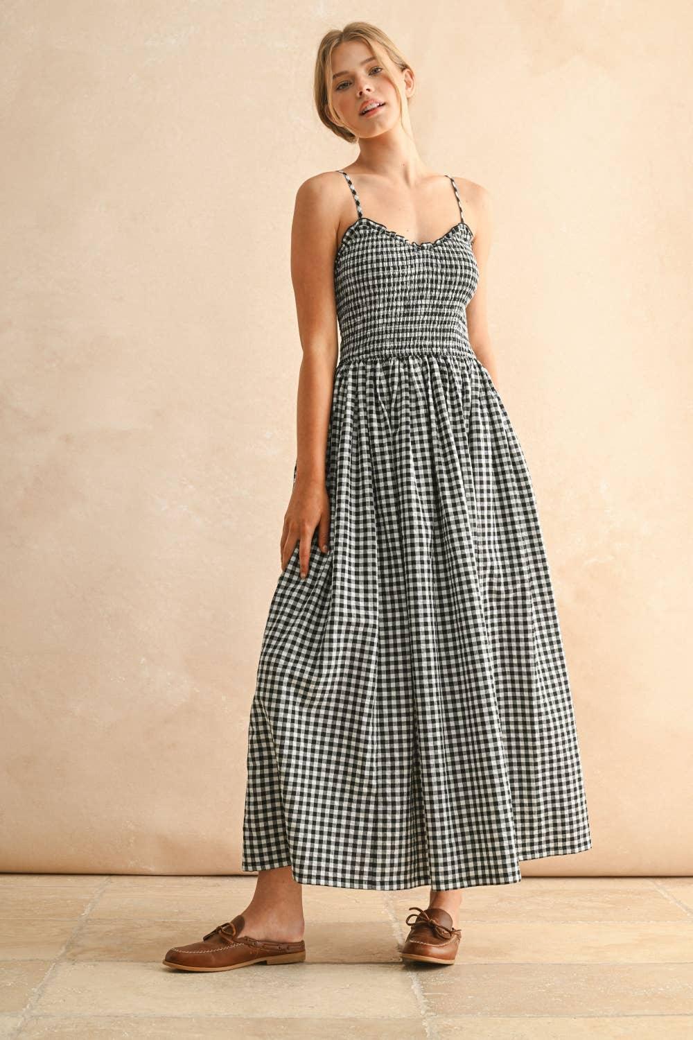 Woman in black and white gingham midi dress with thin straps and brown loafers