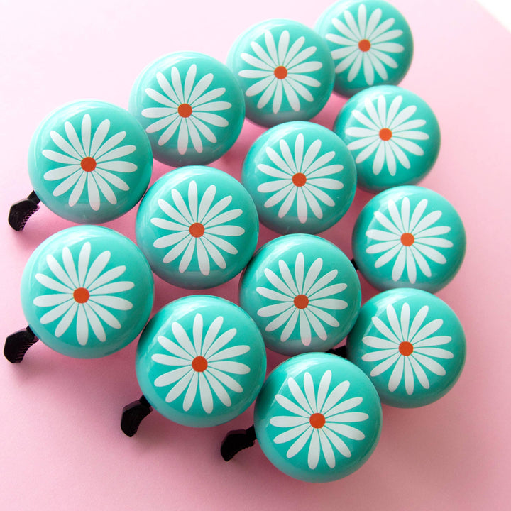 Turquoise bike bells with white daisy design, perfect for coastal adventures and everyday rides.