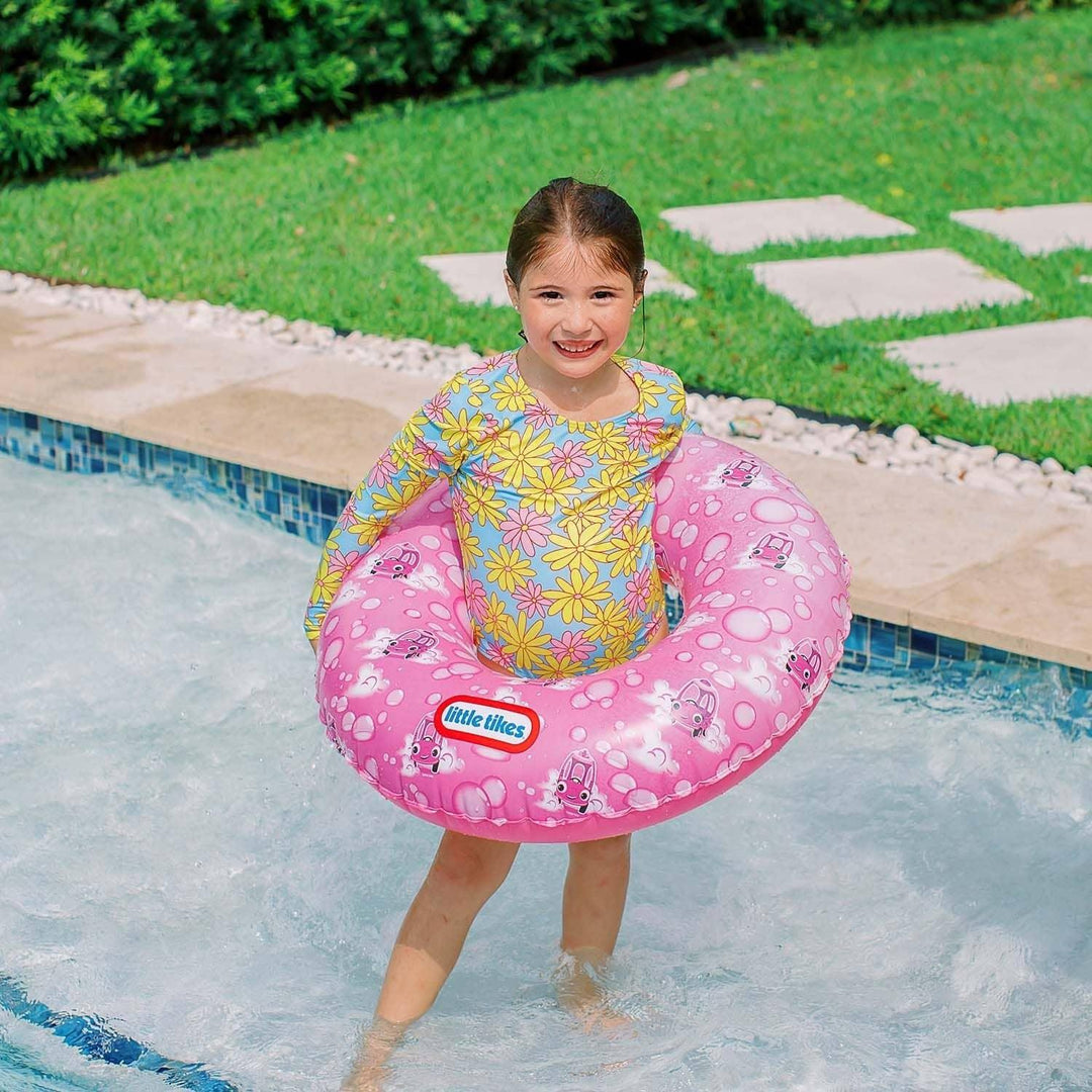 Girl in pool with pink Little Tikes swim ring, floral swimsuit, poolside fun