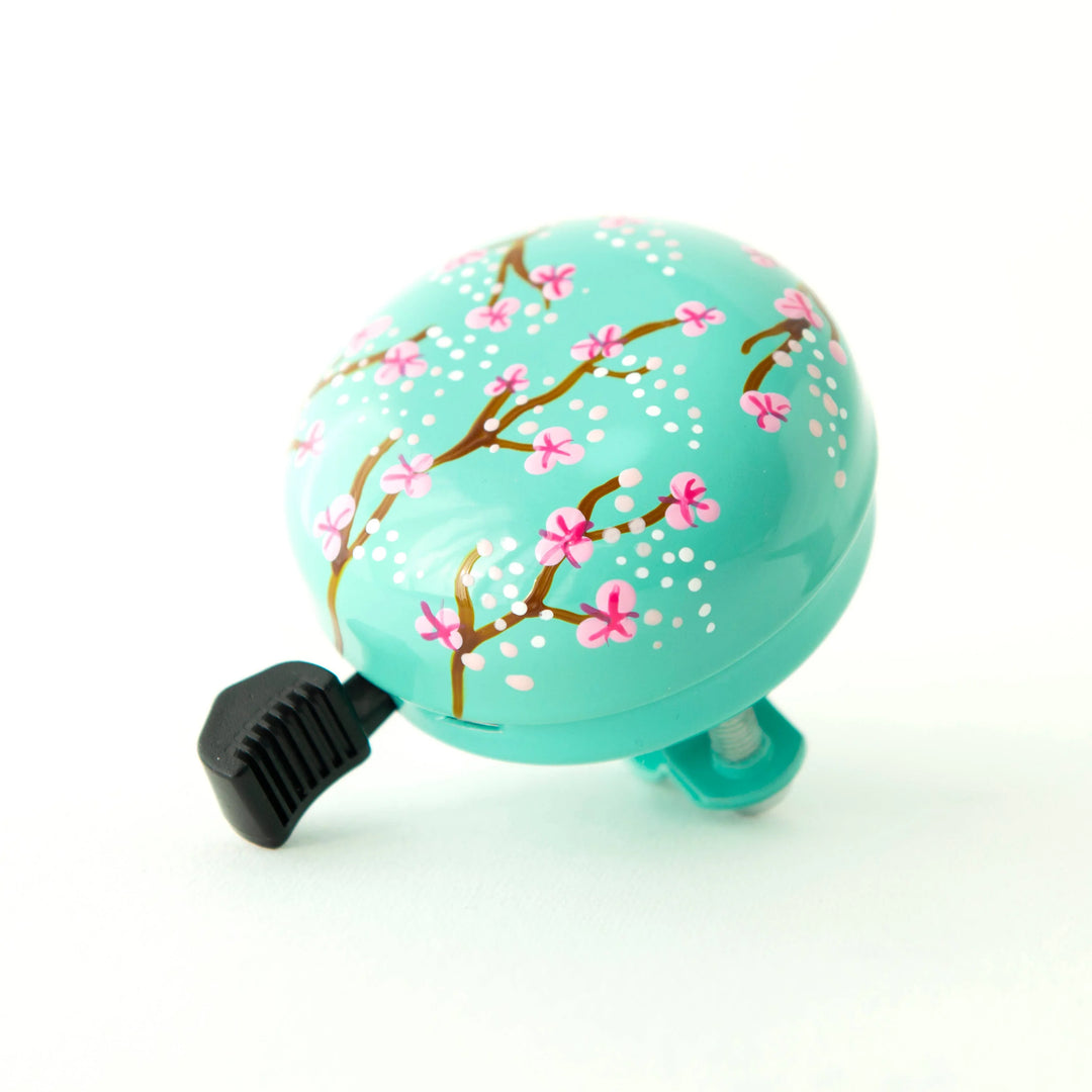 Turquoise bike bell with pink cherry blossom design, perfect for coastal bike rides and outdoor adventures.