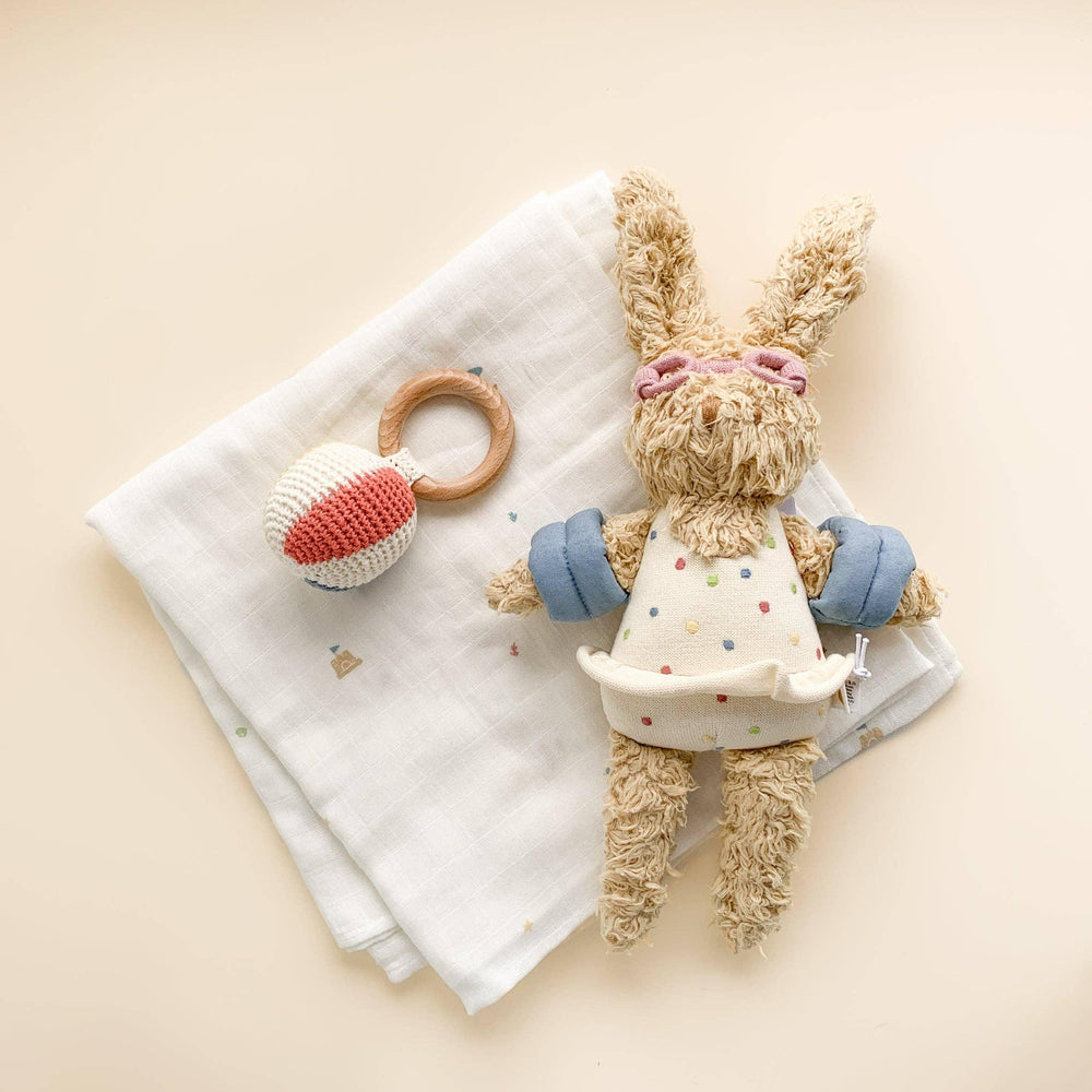 Soft bunny lovey with polka dot dress, wooden teether, and muslin blanket for baby comfort and play