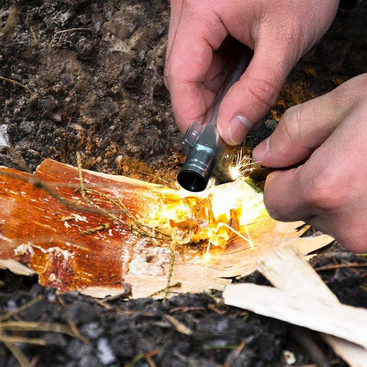 Hands using fire starter to ignite tinder in outdoor setting for camping or survival
