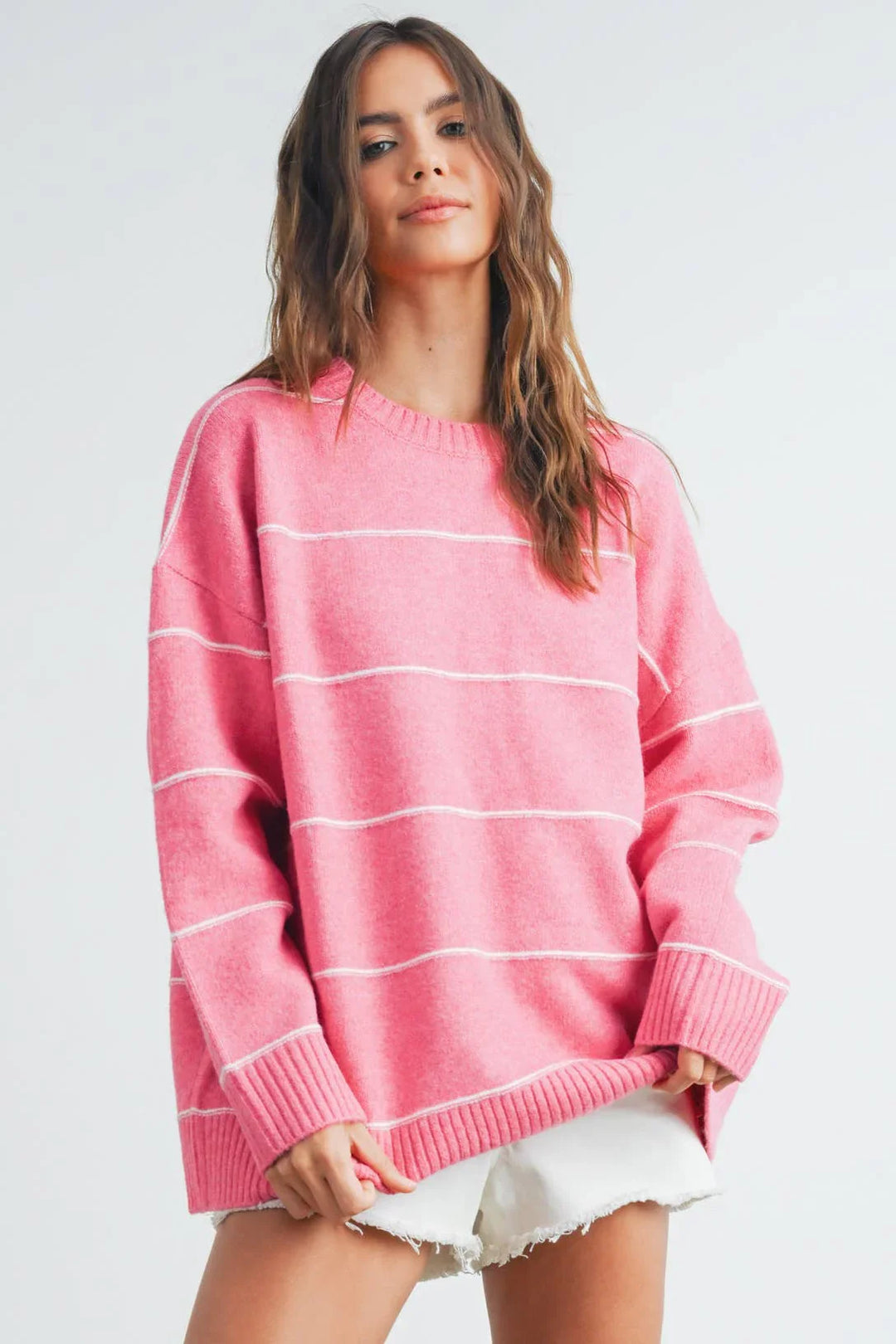 Pink striped oversized sweater with white ribbed cuffs and hem, paired with denim shorts