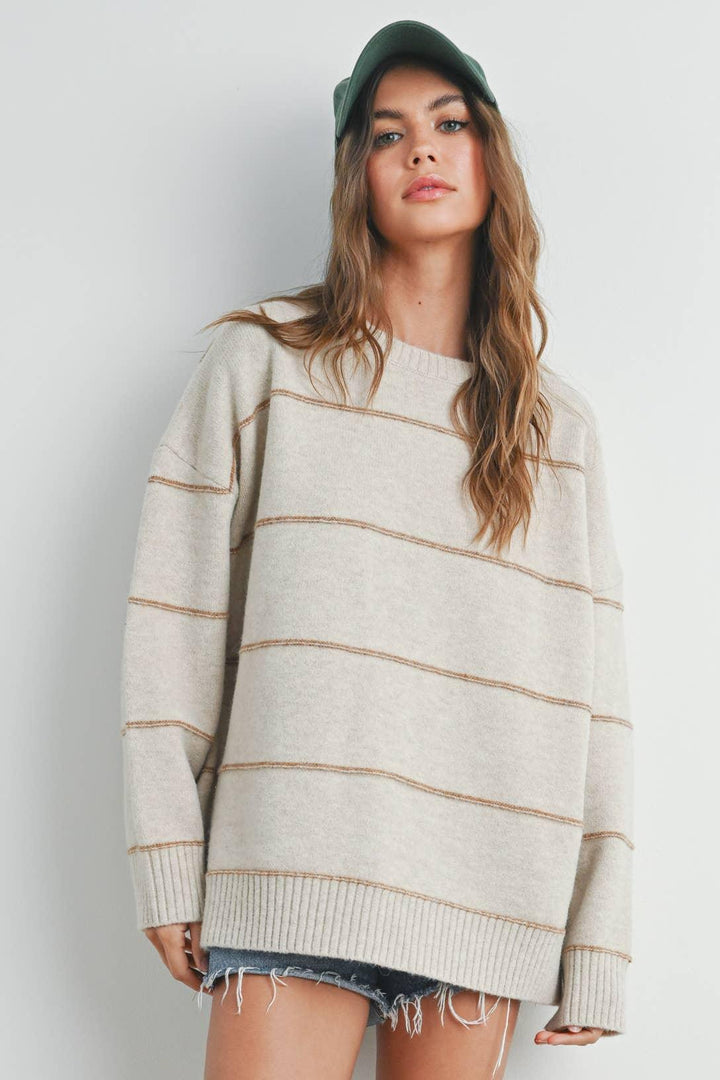 Oversized striped sweater with ribbed hem, paired with denim shorts and a green cap for casual style