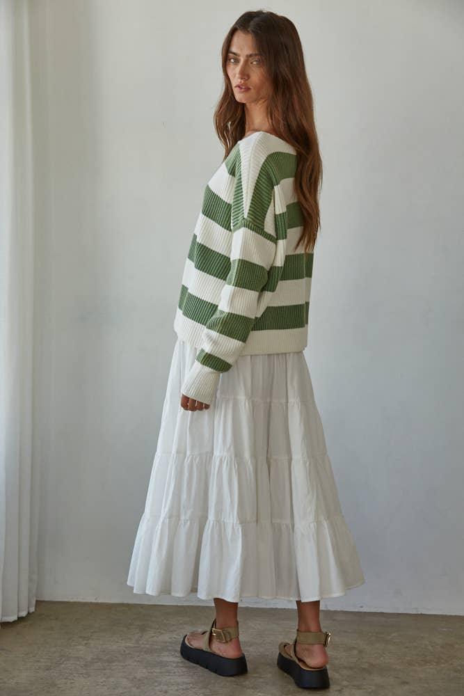 Woman in green and white striped ribbed sweater with tiered white midi skirt and platform sandals