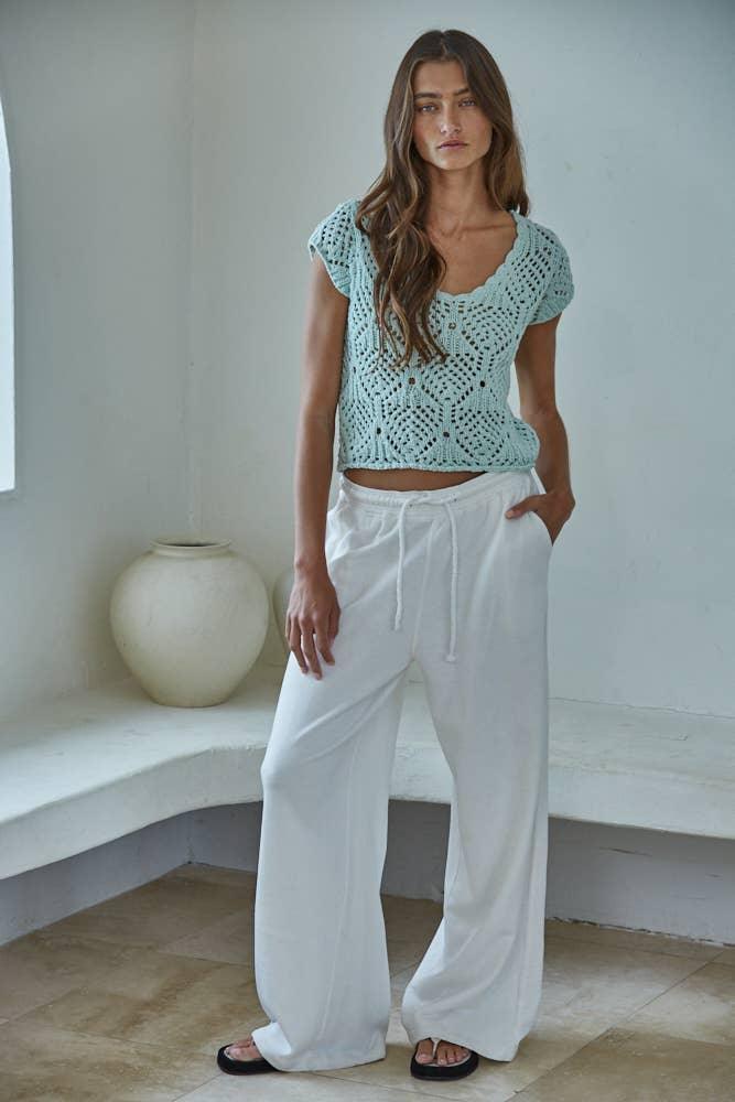 Woman in mint crochet top and white wide-leg pants, casual summer outfit