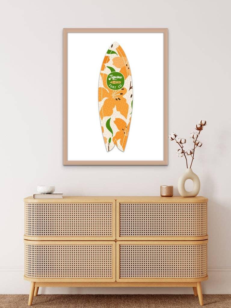 Orange floral surfboard art print in modern frame above rattan console table