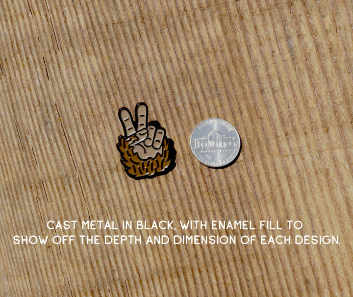 Squatchy Bigfoot Peace enamel pin next to a US quarter on a textured wood background.