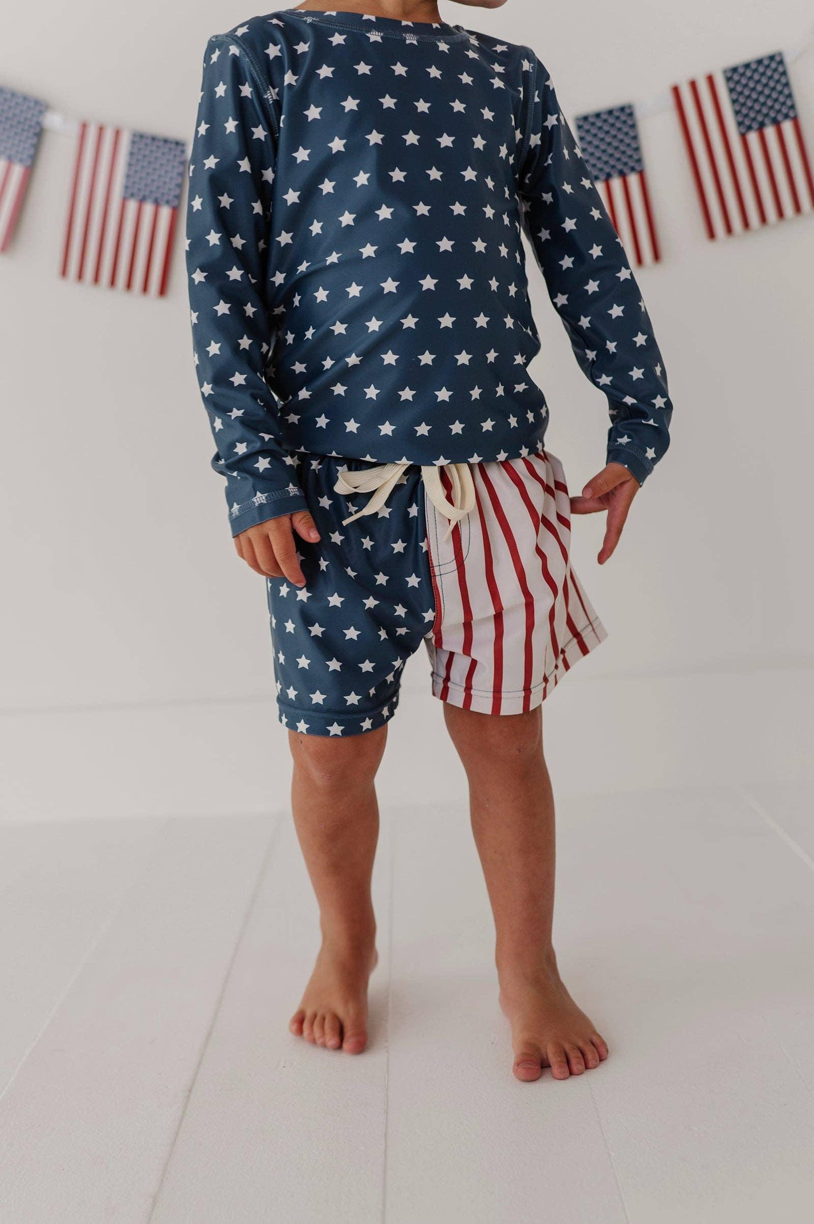 Kid in stars and stripes swim set with American flag bunting, perfect for beach days and coastal adventures.
