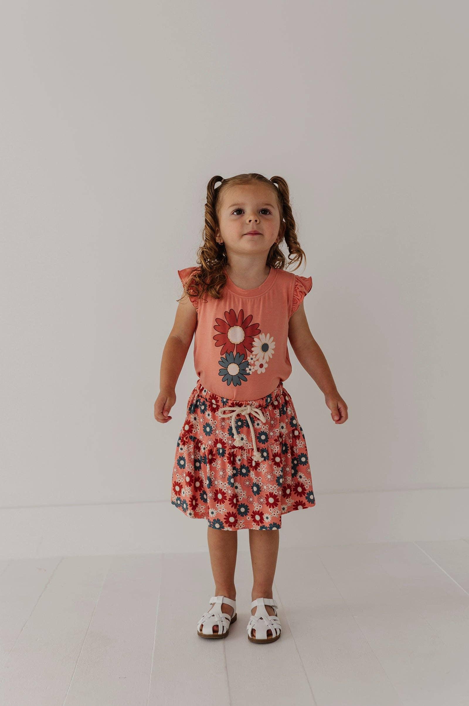 Toddler in coral floral dress with ruffle sleeves and matching skirt, white sandals, pigtails