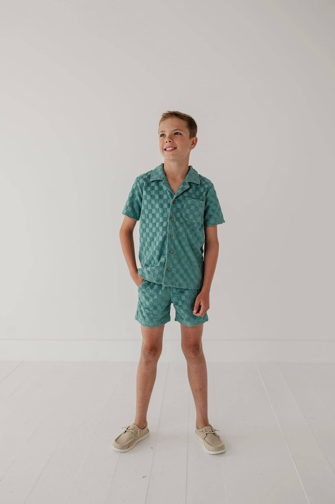 Boy in teal checkered short sleeve shirt and matching shorts, coastal style summer outfit