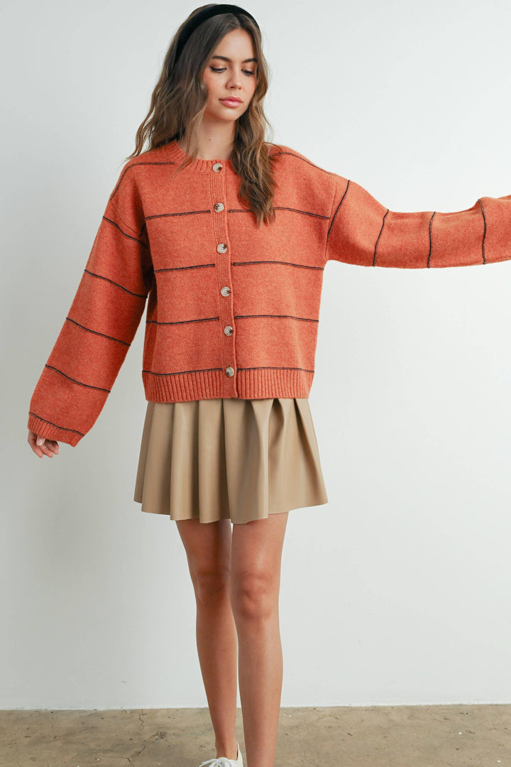 Rust orange striped button-up cardigan with beige pleated skirt, coastal style outfit