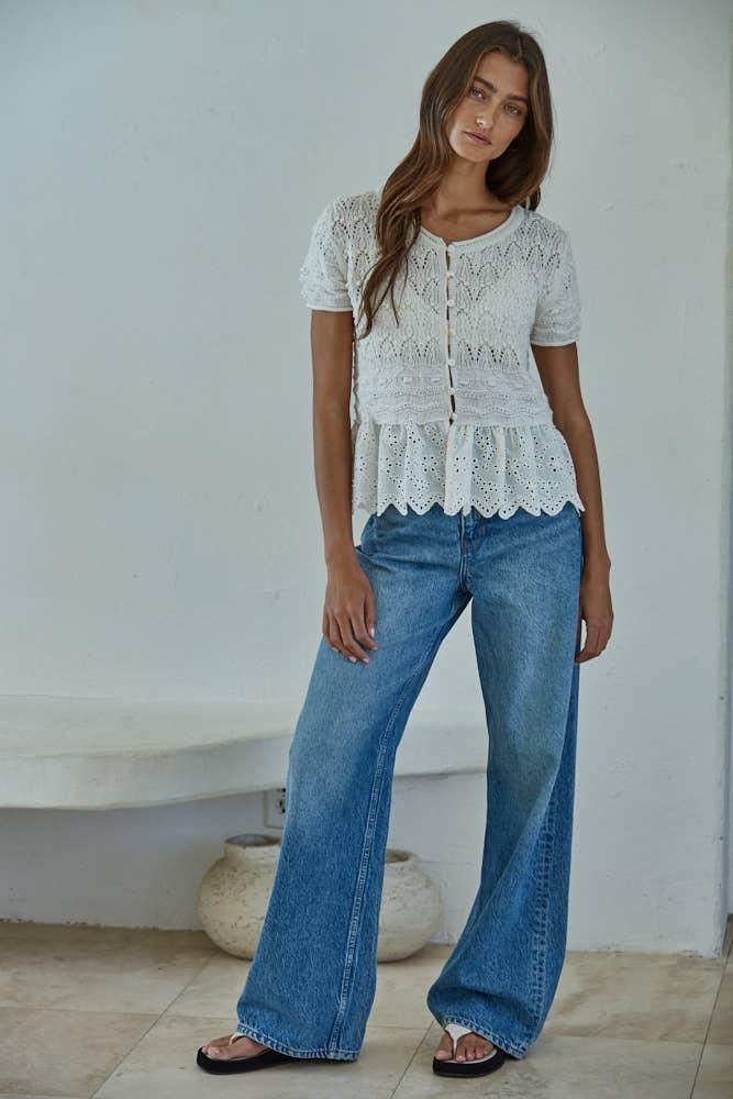 White eyelet peplum top with button front, paired with wide-leg denim jeans for coastal style