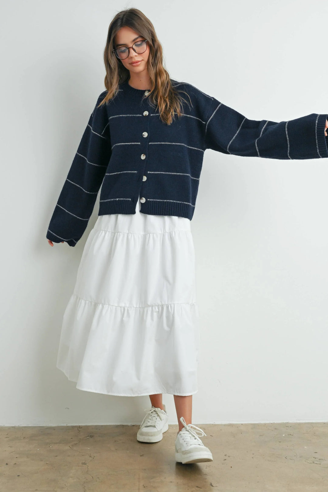 Navy striped cardigan with white tiered midi skirt and sneakers, coastal casual style