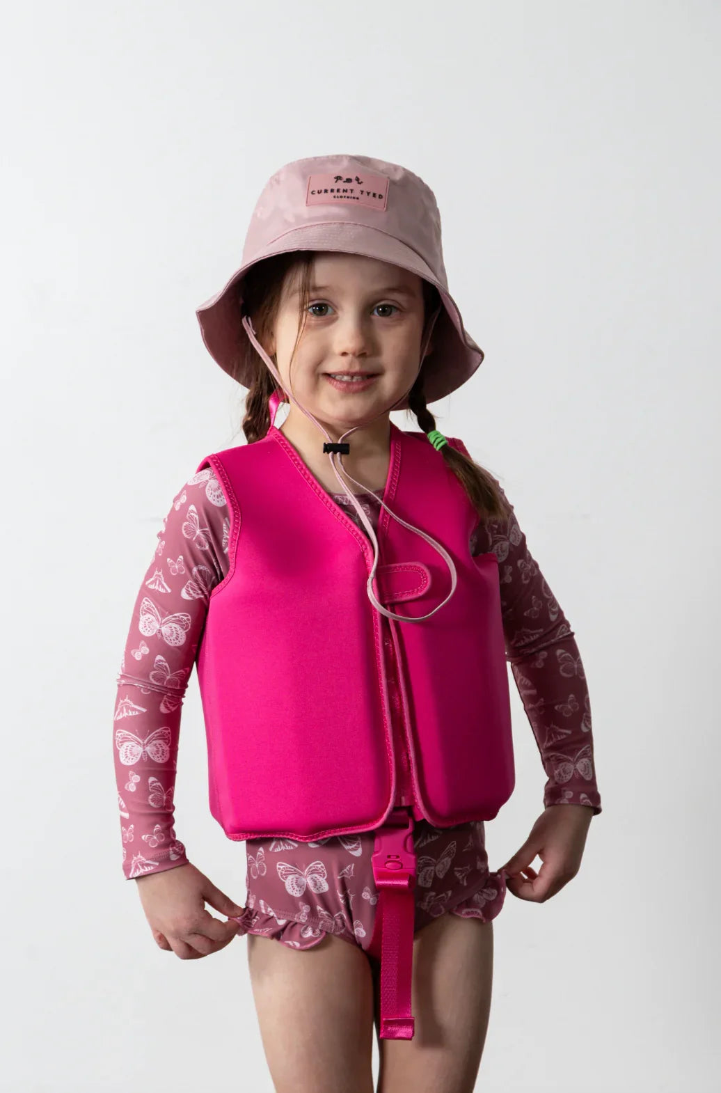 Child in pink swim vest and butterfly rash guard with matching hat for water safety