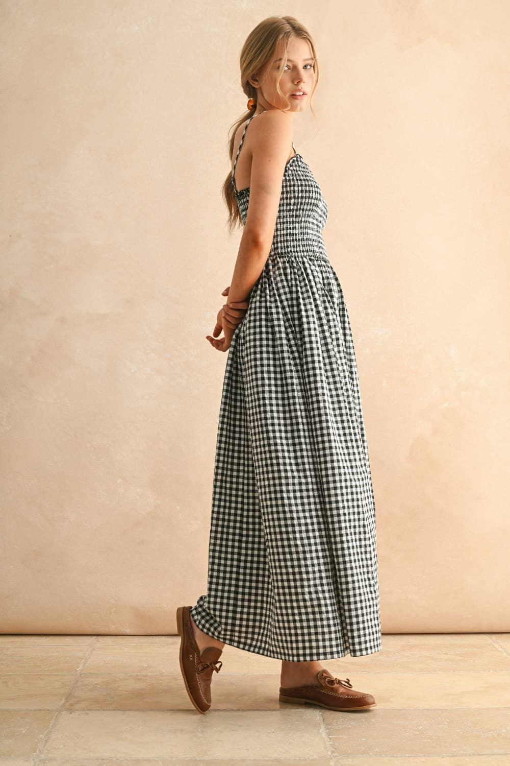 Woman in black and white gingham maxi dress with brown loafers, side view