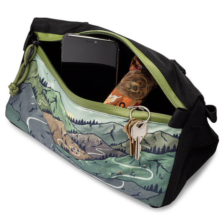Open Oso Supply Co waterproof bike handlebar bag containing a phone, keys, and snack.