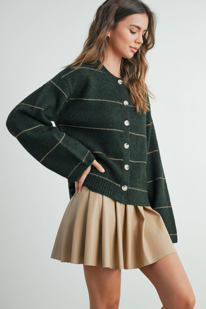 Woman in green striped button-up cardigan with tan pleated skirt, coastal style outfit