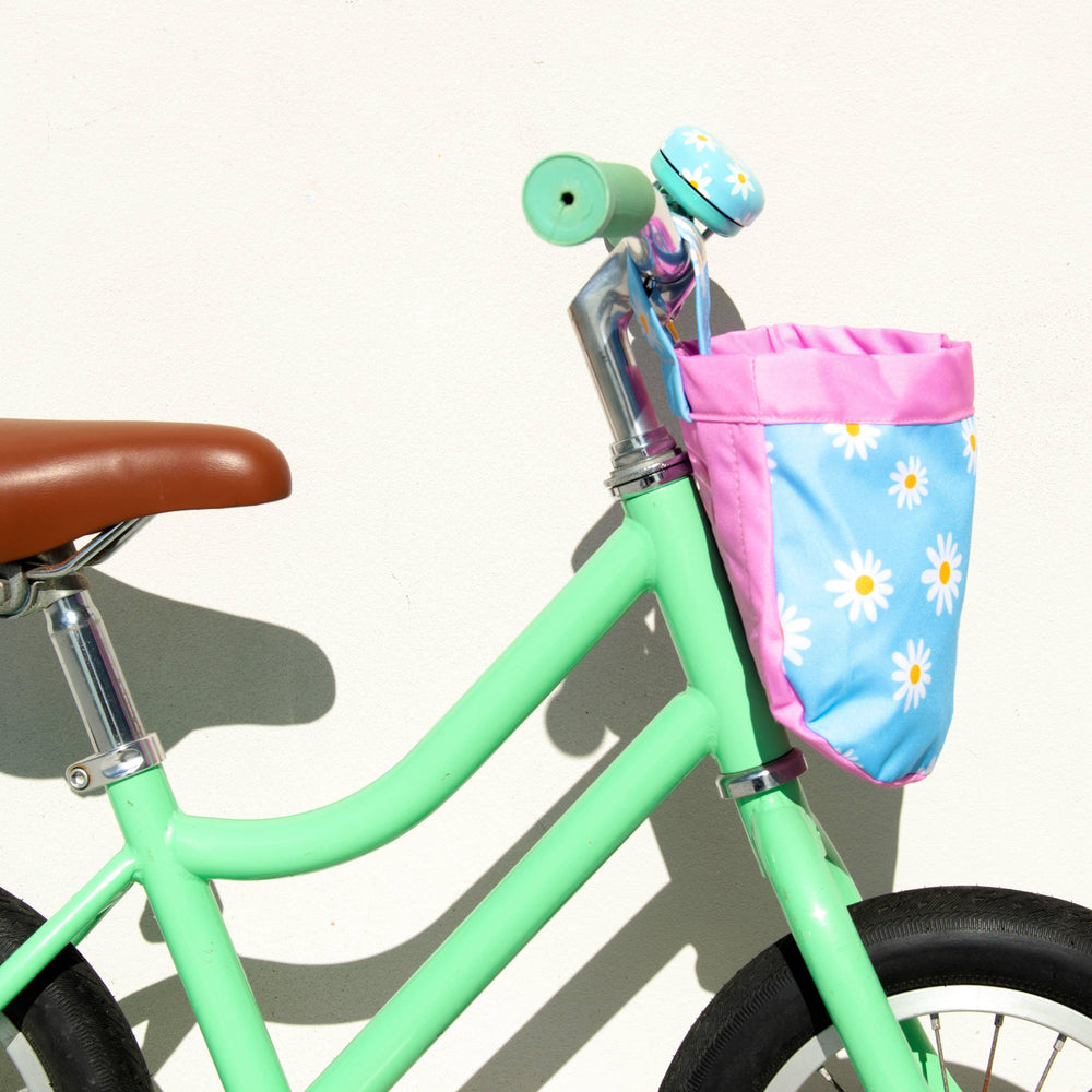 Mint green kids bike with daisy basket, brown seat, and bell for coastal adventures